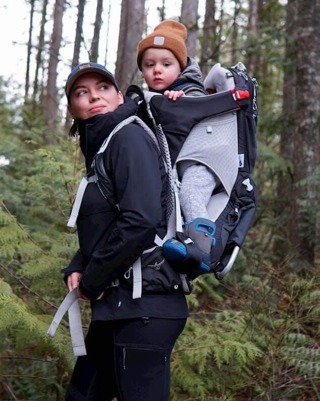 赤ちゃんを抱っこして森をハイキングする母親