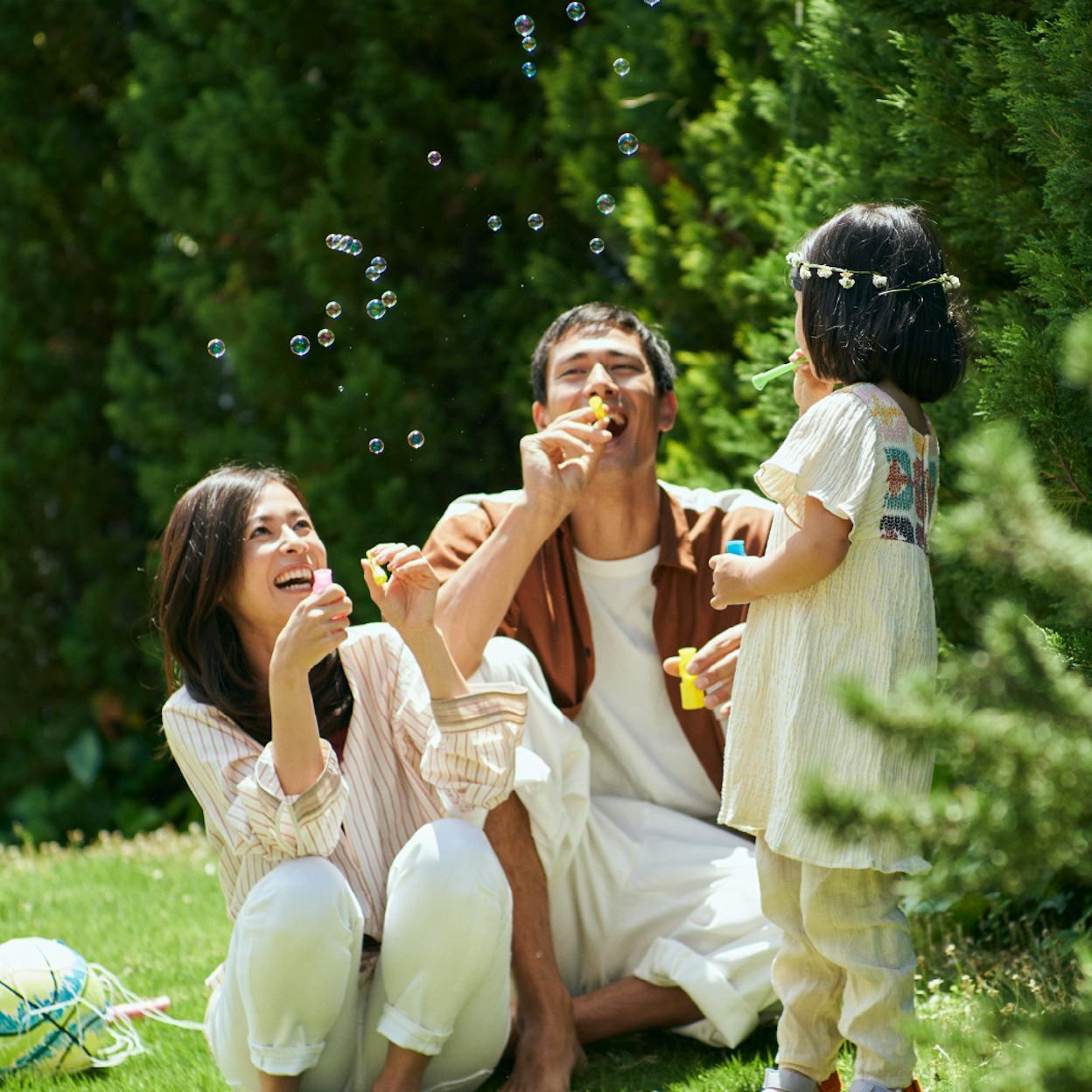 男性と女性と子供がシャボン玉で楽しそうに遊んでいる写真